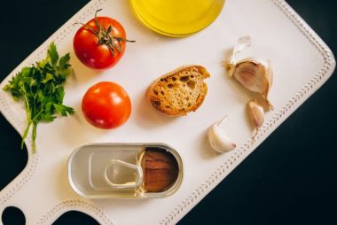 Fresh ingredients for making Catalán toast, including tomatoes, anchovies, and garlic.